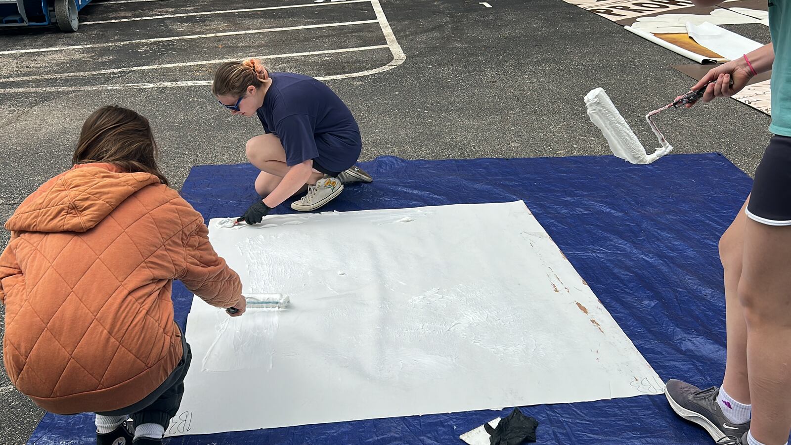 Molly Van Kirk-Butler, Julia Nielsen and Madison Coffee prepare a panel of the parachute cloth mural to be pasted to the side of Mudlick Tap House. STAFF/ZOE HILL