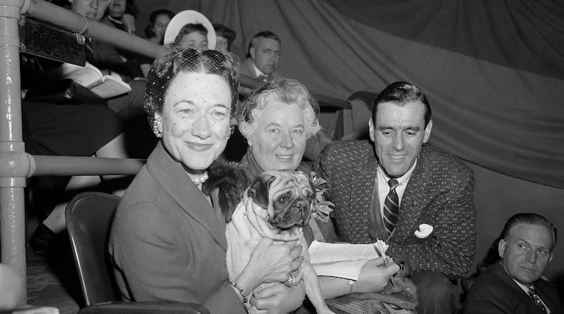 FILE - The Duchess of Windsor, Wallis Simpson, left, holds Ch. Pugville's Golden Victory during judging of the pug class during the Westminster Kennel Club Show at Madison Square Garden in New York, Feb. 13, 1956, as the dog's owner, Arnold Canton, far right, and dog breeder Harriet Smith, look on. (AP Photo/Jacob Harris, File)