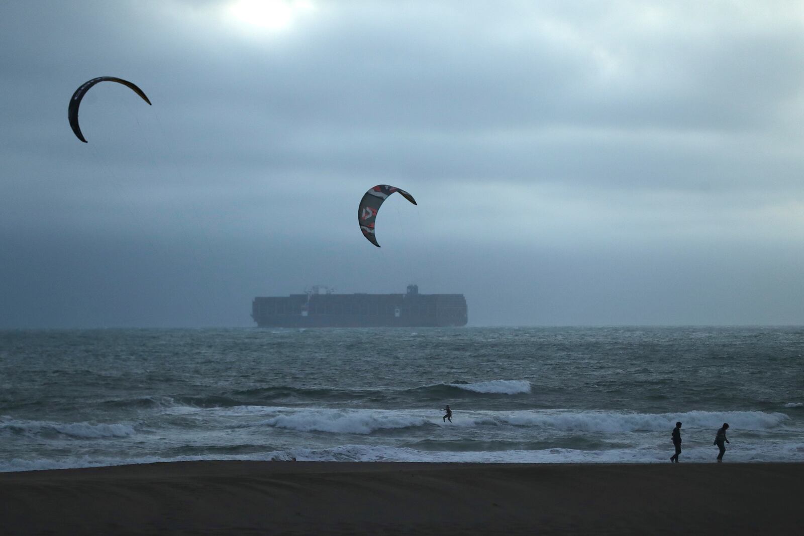 During a tsunami advisory triggered by an underwater earthquake off the coast of Russia, a pair of kite surfers recreate near two beach walkers at Ocean Beach in San Francisco on Tuesday, July 29, 2025. (Scott Strazzante/San Francisco Chronicle via AP)