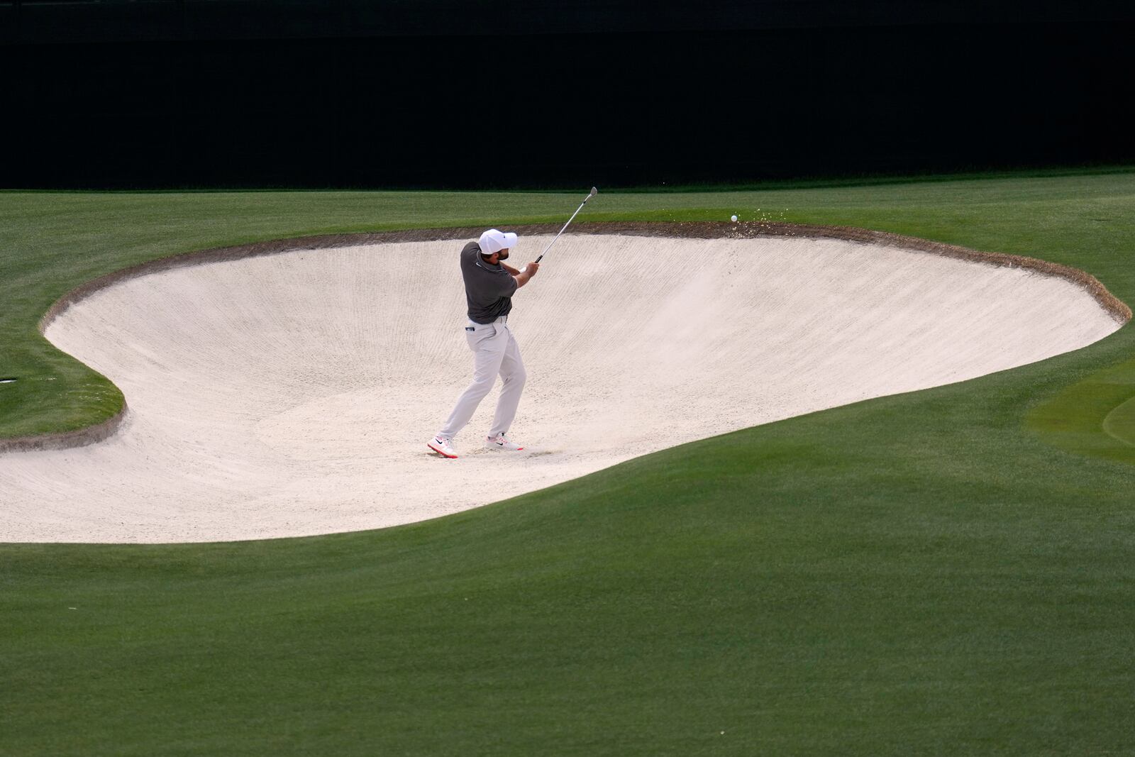 Scottie Scheffler hits from the bunker on the fourth hole during the third round at the Masters golf tournament, Saturday, April 12, 2025, in Augusta, Ga. (AP Photo/George Walker IV)