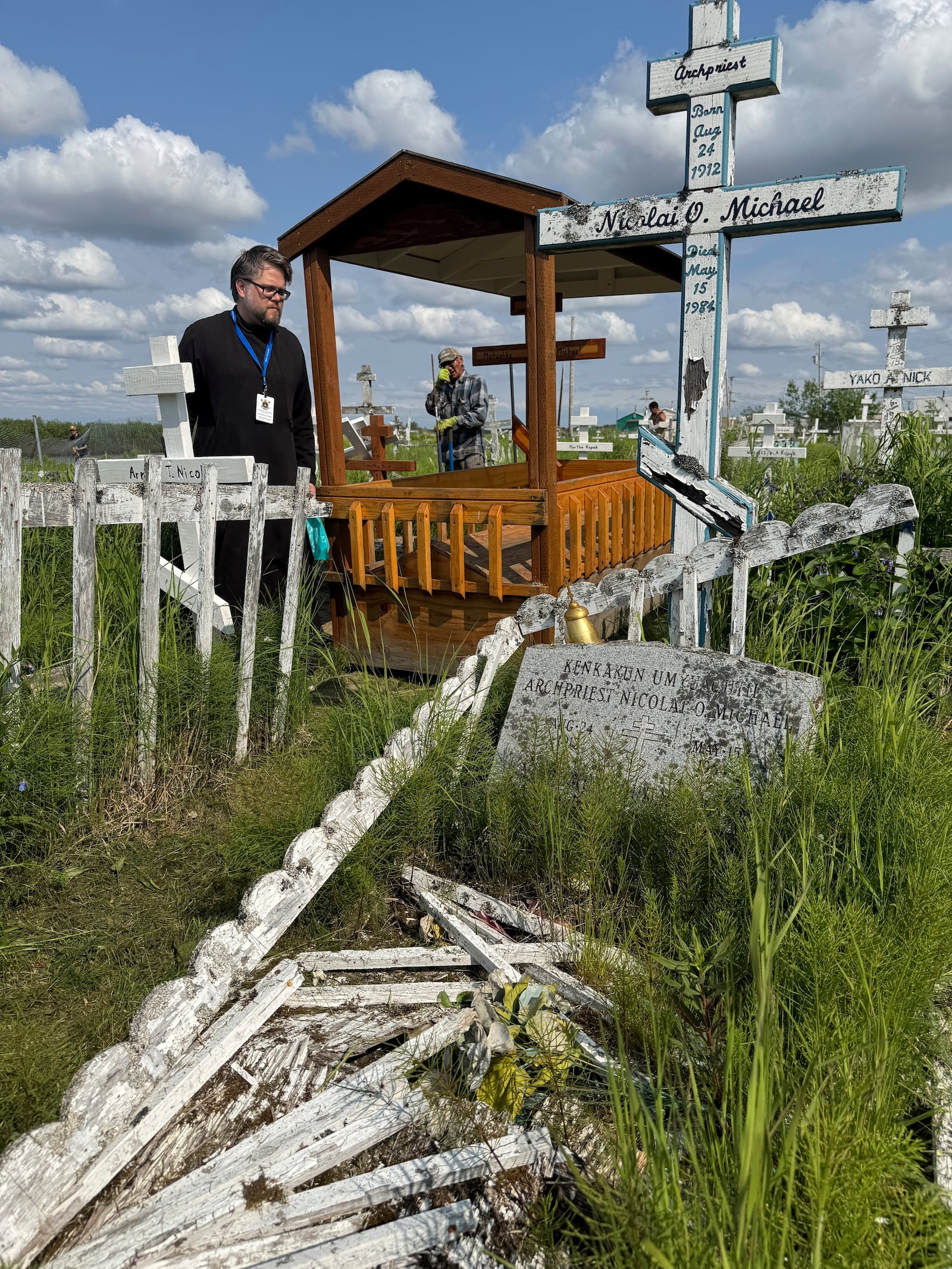 Deacon Michael Lucius of Toronto visits the gravesite of Matushka Olga Michael in Kwethluk, Alaska, on June 18, 2025, a day before she became the first female Orthodox saint in North America. In the foreground is the grave of Olga's husband, Nicolai Michael, who was a priest in Kwethluk. (AP Photo/Mark Thiessen)