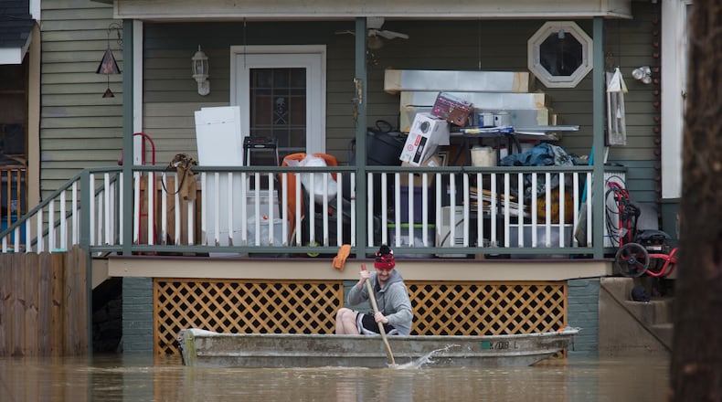 A man paddles his boat alongside a home in the East End along the Ohio River, Saturday, Feb. 24, 2018, in Cincinnati. Forecasters expected the Ohio River could reach levels not seen since the region's deadly 1997 floods. (Liz Dufour/The Cincinnati Enquirer via AP)
