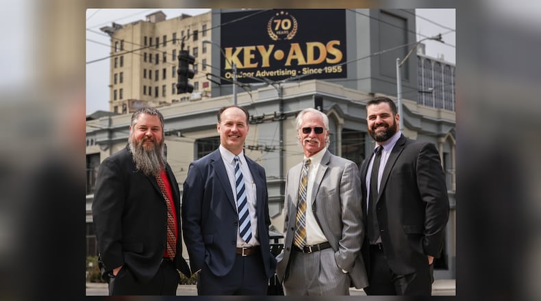 From left to right, Stephen Keyes, Nick Keyes Jr., Nick Keyes Sr. and Joe Keyes pose with Key Ads building on East Third Street in downtown Dayton behind them. Nick Keyes Sr. and his three sons own the business, which is celebrating its 70th anniversary. Nick Keyes Sr.'s father Ed started the business in 1955. BRYANT BILLING / STAFF