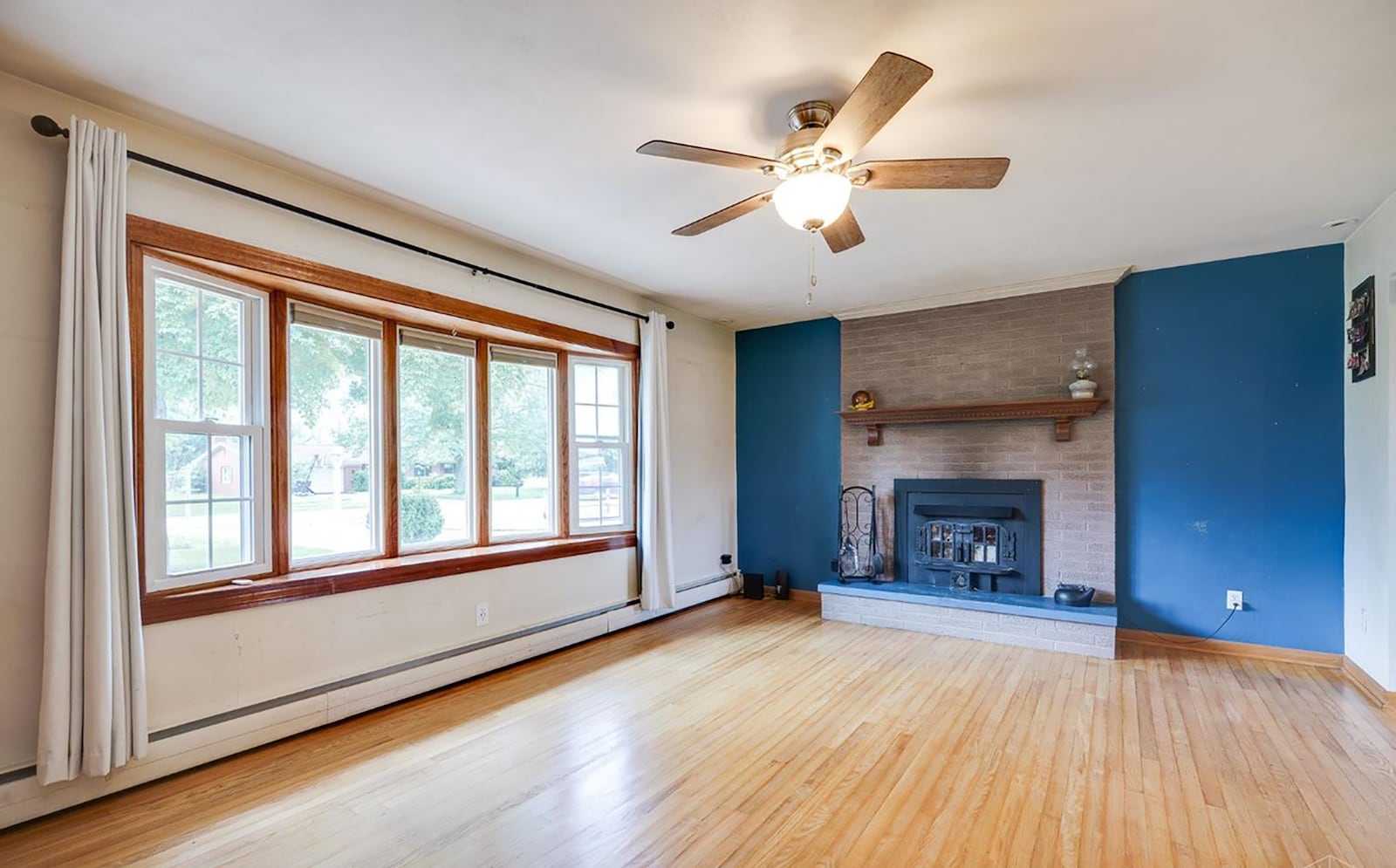 The living room features a woodburning fireplace, hardwood flooring and a ceiling fan. CONTRIBUTED