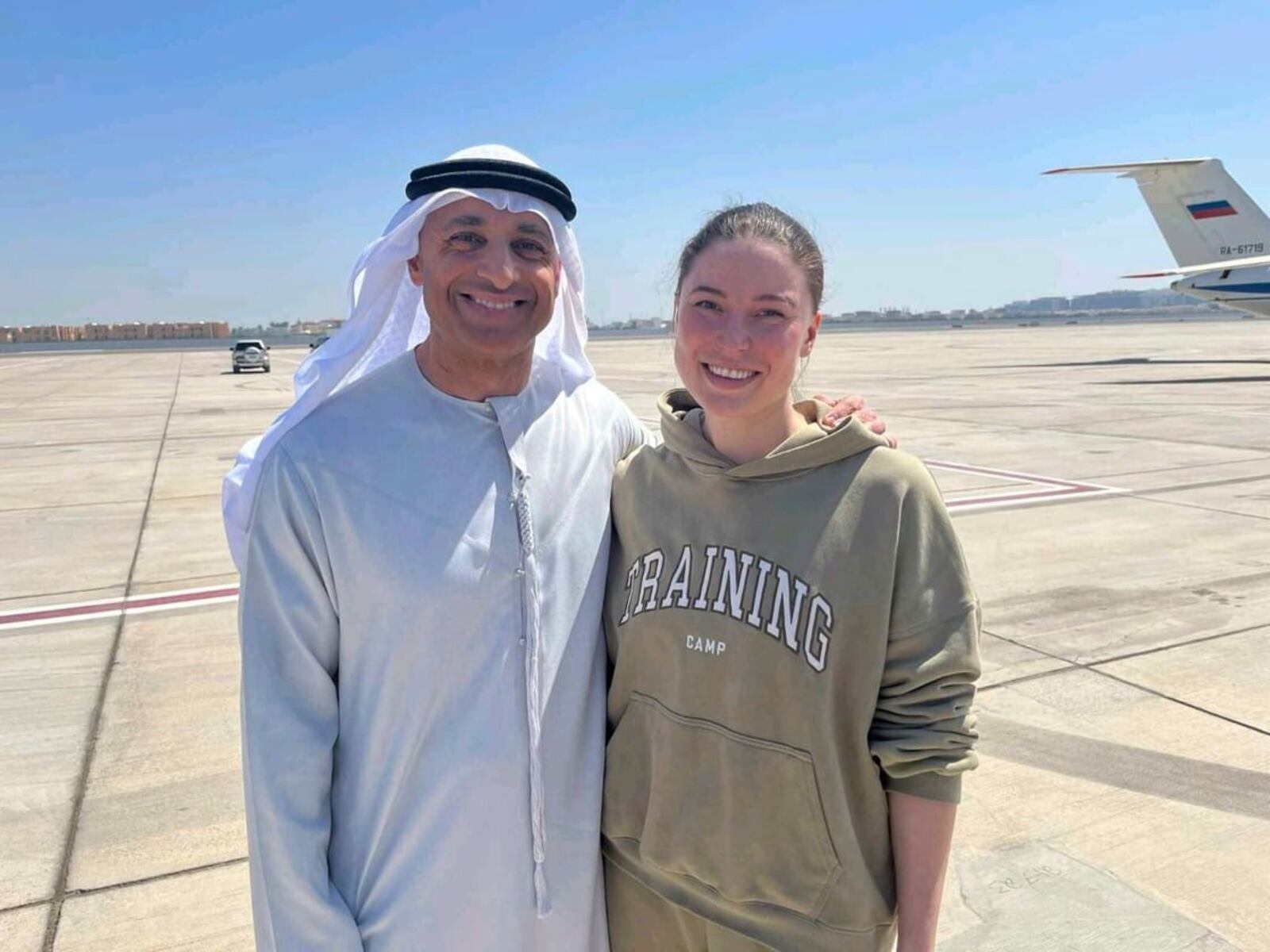 This photo released by the state-run WAM news agency shows Yousef al-Otaiba, the UAE ambassador to the U.S., left, standing next to U.S.-Russian dual national Ksenia Karelina after her release at an airport in Abu Dhabi, United Arab Emirates, Thursday, April 10, 2025. (WAM via AP)