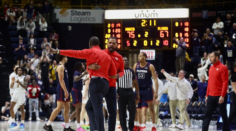 Dayton's Ricardo Greer holds back Anthony Grant as Grant argues a call late in the second half against Chattanooga in the second round of the National Invitation Tournament on Saturday, March 22, 2025, at McKenzie Arena in Chattanooga, Tenn. David Jablonski/Staff
