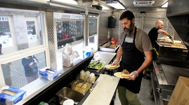 Will Bigham, owner of The Improper Pig, works with Darius Amidi as they serve lunch in The Oinker, the restaurant's food truck, at the Salvation Army's Center of Hope in Charlotte, N.C., on March 14, 2017. (David T. Foster III/Charlotte Observer/TNS)