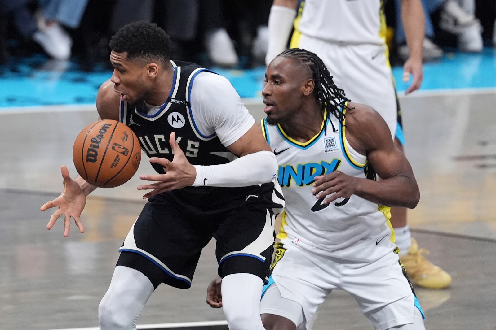 Milwaukee Bucks' Giannis Antetokounmpo, left, tries to keep control of the ball as Indiana Pacers' Aaron Nesmith, right, defends during the first half of a first-round NBA basketball playoff game, Saturday, April 19, 2025, in Indianapolis. (AP Photo/Michael Conroy)