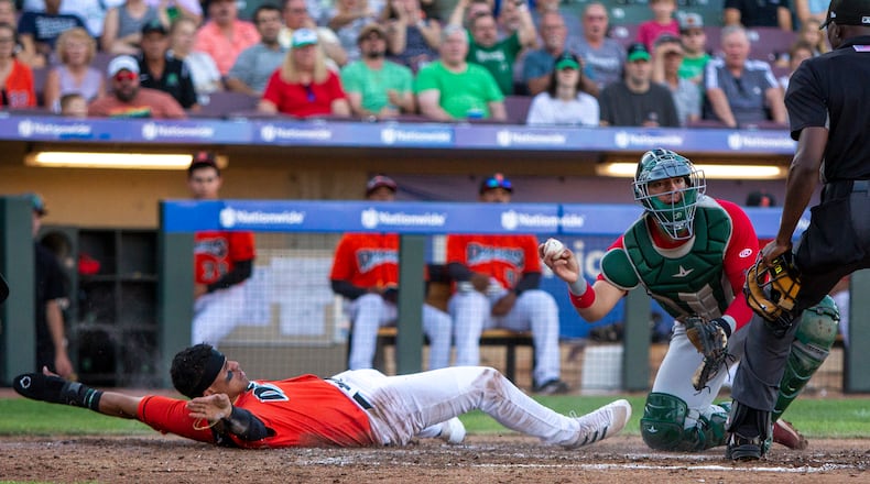 Dayton's Daniel Vellojin signals safe after he was called out on a tag by Fort Wayne catcher Brandon Valenzuela during Friday night's game against Fort Wayne. Vellojin was trying to score from second on Austin Hendrick's bases loaded single in the third inning. CONTRIBUTED/Jeff Gilbert
