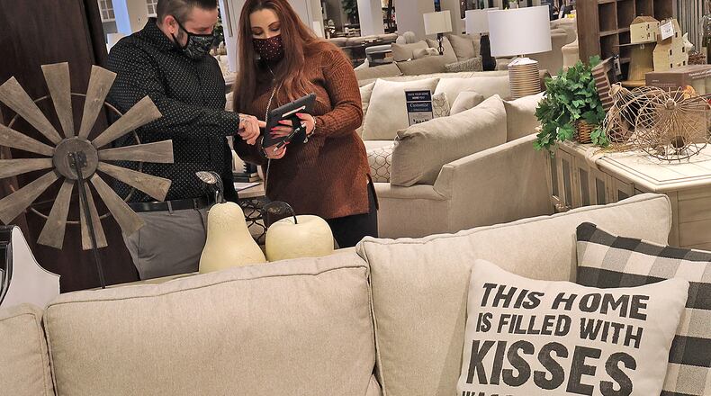 Morris Home Furniture sales professionals David Crist and Michaela Lisch check inventory on a product Friday at Morris' Beavercreek store. BILL LACKEY/STAFF