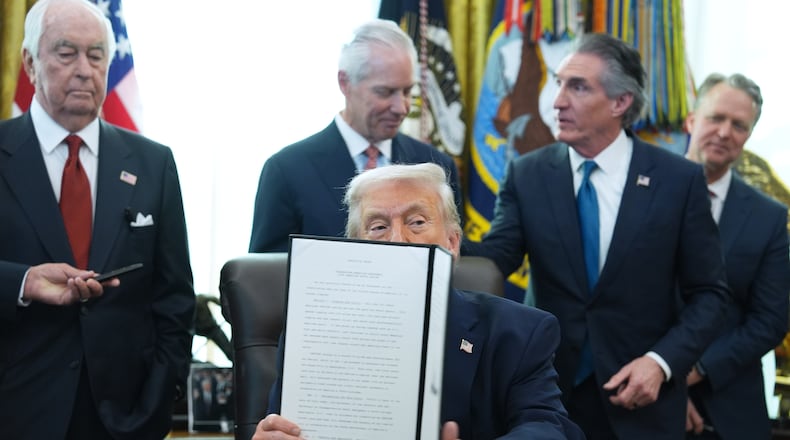 President Donald Trump holds an executive order he signed in the Oval Office of the White House, Friday, Jan. 30, 2026, in Washington. (AP Photo/Evan Vucci)
