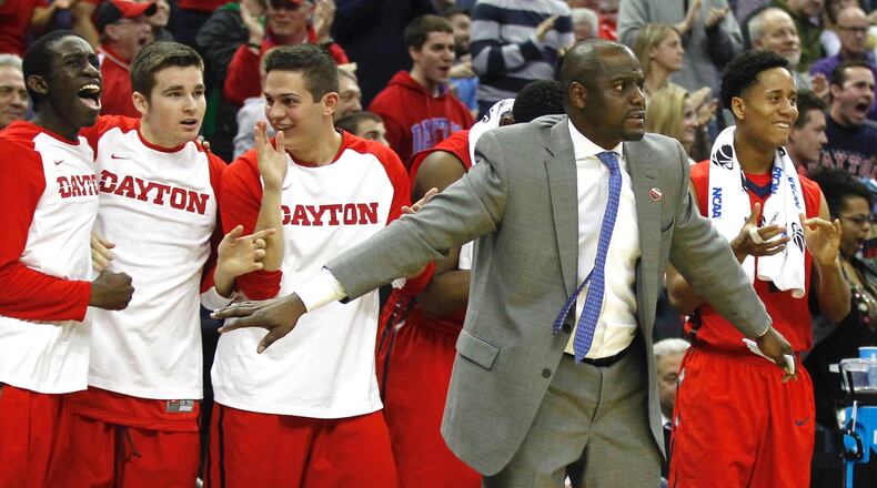 Dayton players and assistant coach Allen Griffin, second from right, watch from the bench in the final minute of a victory against Providence in the second round of the NCAA tournament on Friday, March 20, 2015, at Nationwide Arena in Columbus. David Jablonski/Staff