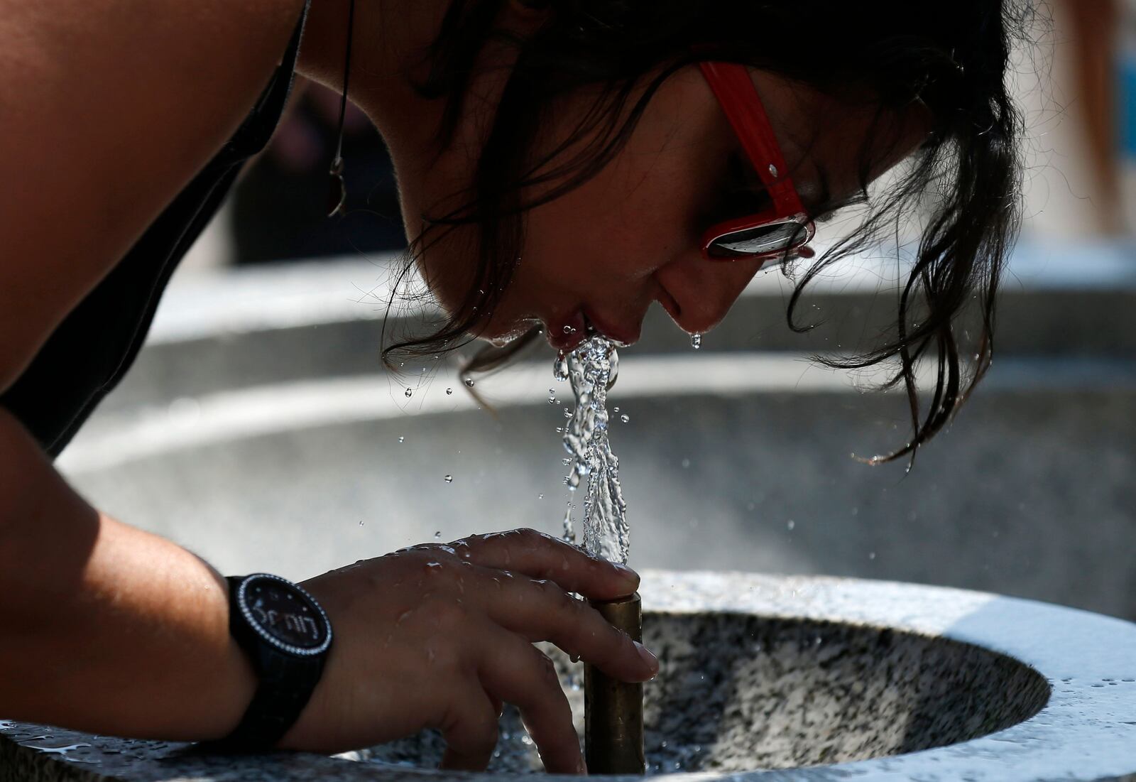 A woman drinks from a water fountain in Green Park in London.