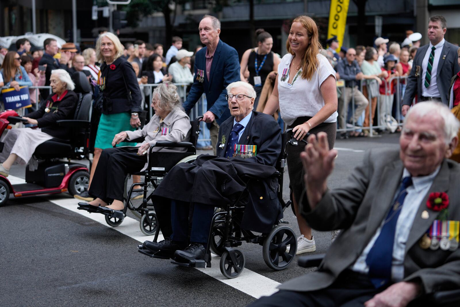Participants are assisted as they march past thousands of people lining the street to pay tribute to their war dead during the Anzac Day parade in Sydney, Australia, Friday, April 25, 2025. (AP Photo/Rick Rycroft)