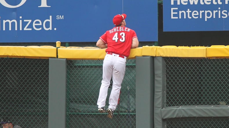 Reds right fielder Scott Schebler climbs the wall but can't get a home run hit by the Rockies on Sunday, May 21, 2017, at Great American Ball Park in Cincinnati. David Jablonski/Staff