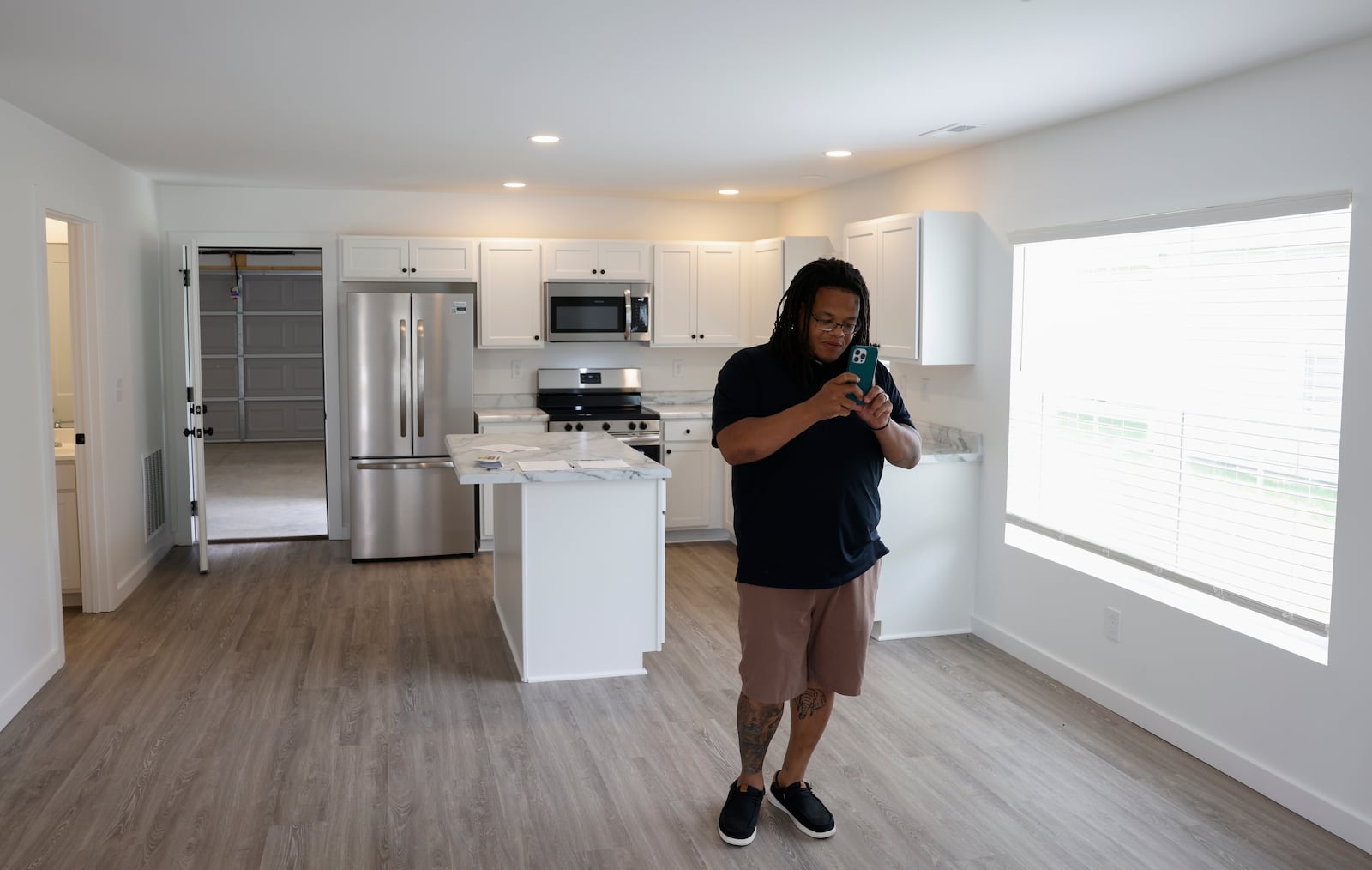 Tyler Hicks, board of directors member for Neighborhood Housing Partnership, photographs a living room during an open house celebration of the construction of seven homes on Clifton Avenue on Monday, June 9, 2025, in Springfield. JOSEPH COOKE/STAFF