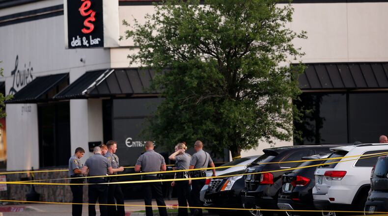 Police officers stand at the scene of a shooting on the east side of Lake Hefner in Oklahoma City, Thursday, May 24, 2018. A man armed with a pistol walked into Louies On The Lake restaurant at the dinner hour and opened fire, wounding two customers, before being shot dead by a handgun-carrying civilian in the parking lot, police said.