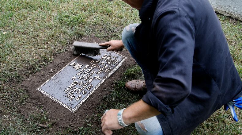 Rob Kelly, a member of the Ferncliff Cemetery grounds crew, brushes off the new grave marker for Medal of Honor winner and Clark County native James Richard Ward after placing it in the World War II veterans section at Ferncliff Wednesday, July 10, 2024. The remains of Ward, who was killed on the USS Oklahoma at Pearl Harbor, were recently recovered and identified. His family asked for him to be buried at Arlington Cemetery in Washington D.C. and according to military rules, a veteran can only have one military grave marker and the marker that was placed at Ferncliff was removed. The cemetery recently had another marker made and today it was placed where the old marker was located. BILL LACKEY/STAFF