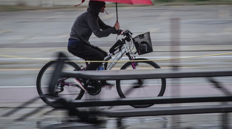 A cyclist speeds down East Fifth St. Thursday June 3, 2021 dodging rain and cars at the same time. JIM NOELKER/STAFF