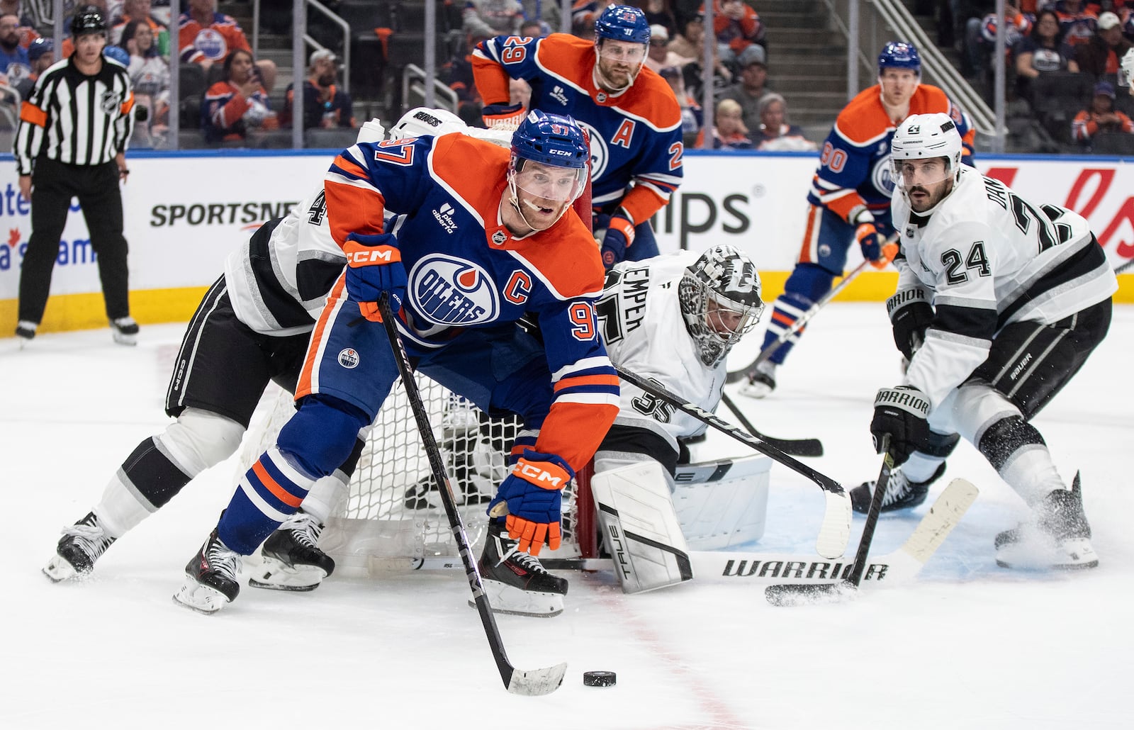 Los Angeles Kings' goalie Darcy Kuemper (35) looks for the puck as Edmonton Oilers' Connor McDavid (97) skates around the net and Kings' Phillip Danault (24) defends during the second period of an NHL hockey playoff game in Edmonton, Alberta, Friday, April 25, 2025. (Jason Franson/The Canadian Press via AP)