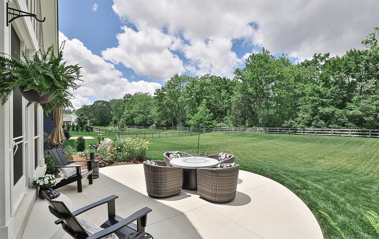 The back yard has mature trees lining the rear and a wood fence. There is also a round concrete patio. CONTRIBUTED