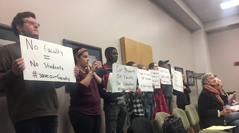 Andrew Blake, left, a senior studying music performance at Wright State, holds a sign to protest recent faculty and staff layoffs during a board of trustees meeting Wednesday. Next to him, Abby Jones and Brendon Sapp also protest. MAX FILBY / STAFF