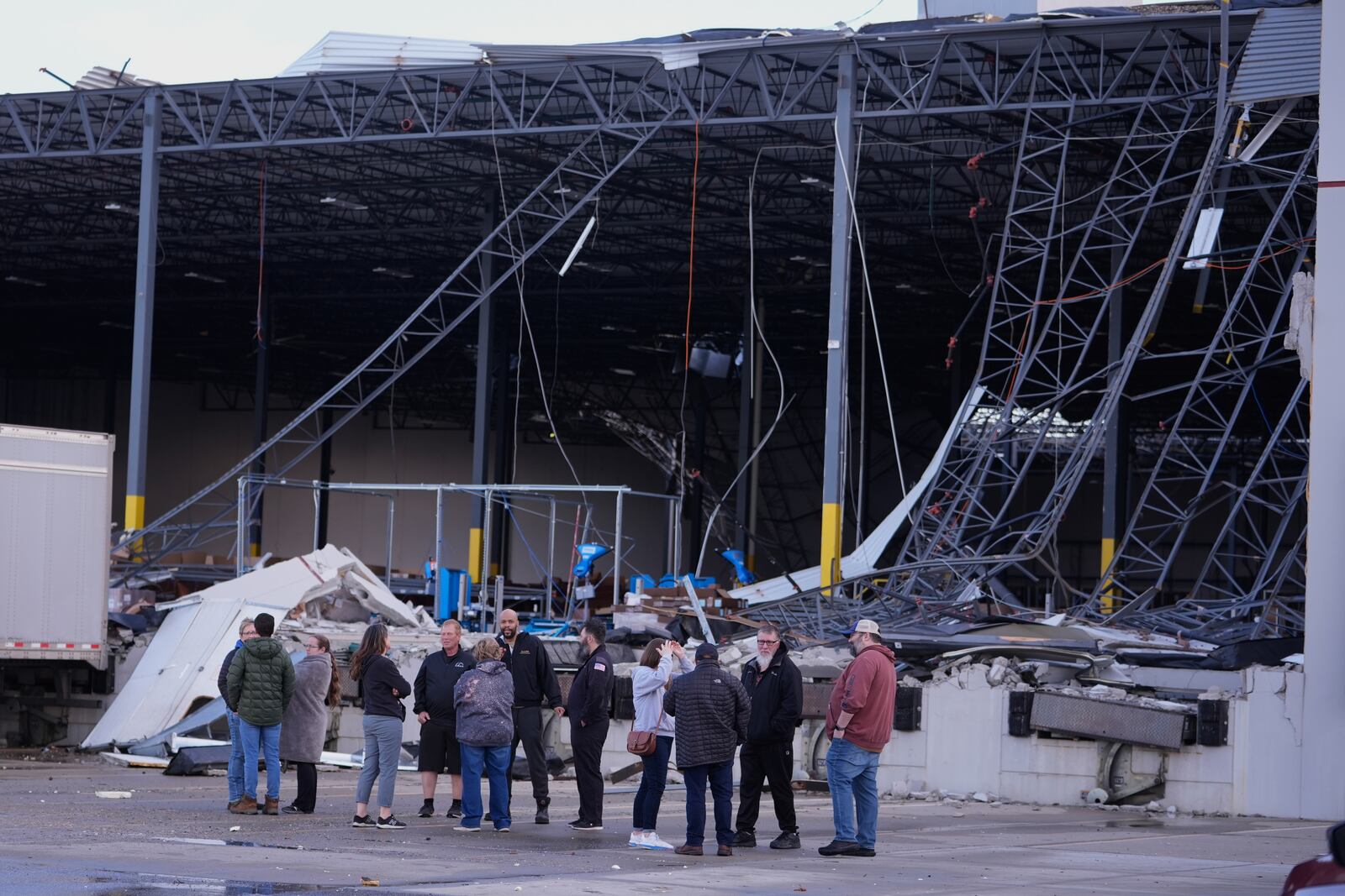 Warehouse workers gather at the site of a storm damaged warehouse in Brownsburg, Ind., Thursday, April 3, 2025. (AP Photo/Michael Conroy)