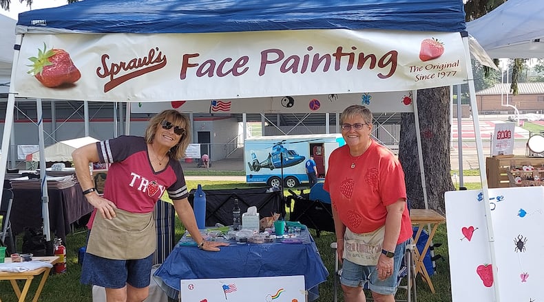 Kim Bramlage (L) and her sister Kari Dillman at the Troy Strawberry Festival this year. The sisters have vowed that they will continue painting faces in honor of their dad, Doug Spraul, who passed away in 2007 but came up with the idea 47 years ago.
