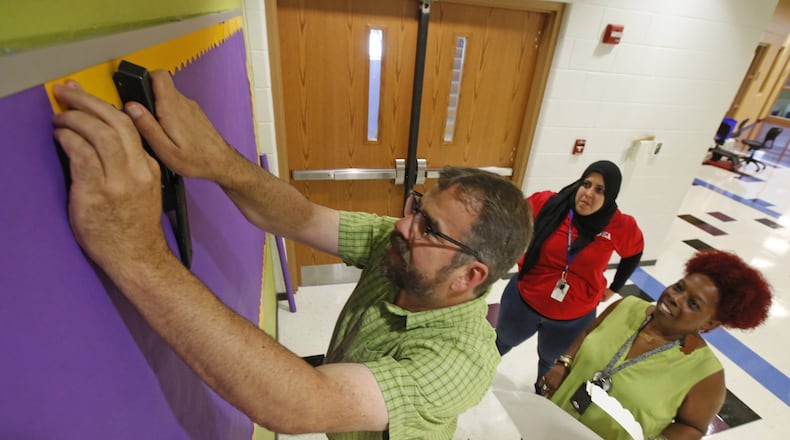 Dayton Public Schools teachers prepare a bulletin board in the Boys Prep Academy on Friday afternoon. Jeff Theis, left, Sophia Shalash and Alva Johnson, right, were busy preparing for classes to begin on Tuesday, August 15. TY GREENLEES / STAFF