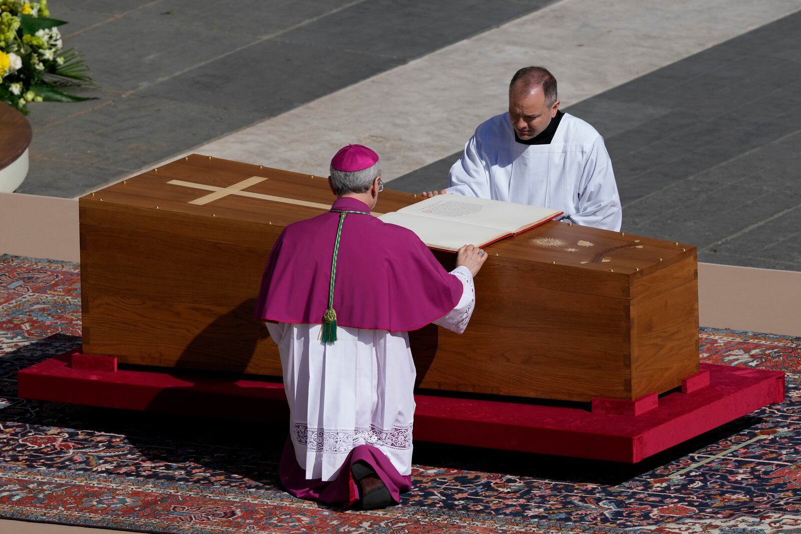 Archbishop Diego Giovanni Ravelli, back to camera, kneels by the coffin of Pope Francis in St. Peter's Square at the Vatican, Saturday, April 26, 2025. (AP Photo/Gregorio Borgia)