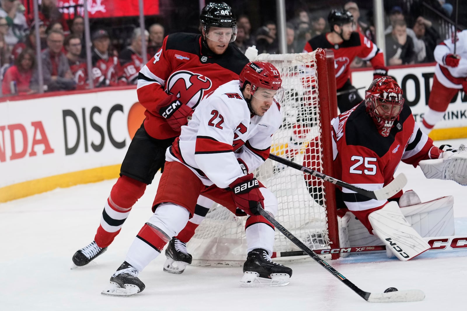 Carolina Hurricanes' Logan Stankoven, center, brings the puck around the net as New Jersey Devils goaltender Jacob Markstrom, right, and Dennis Cholowski look on during the first period of Game 4 of an NHL hockey first-round series, Sunday, April 27, 2025, in Newark, N.J. (AP Photo/Seth Wenig)