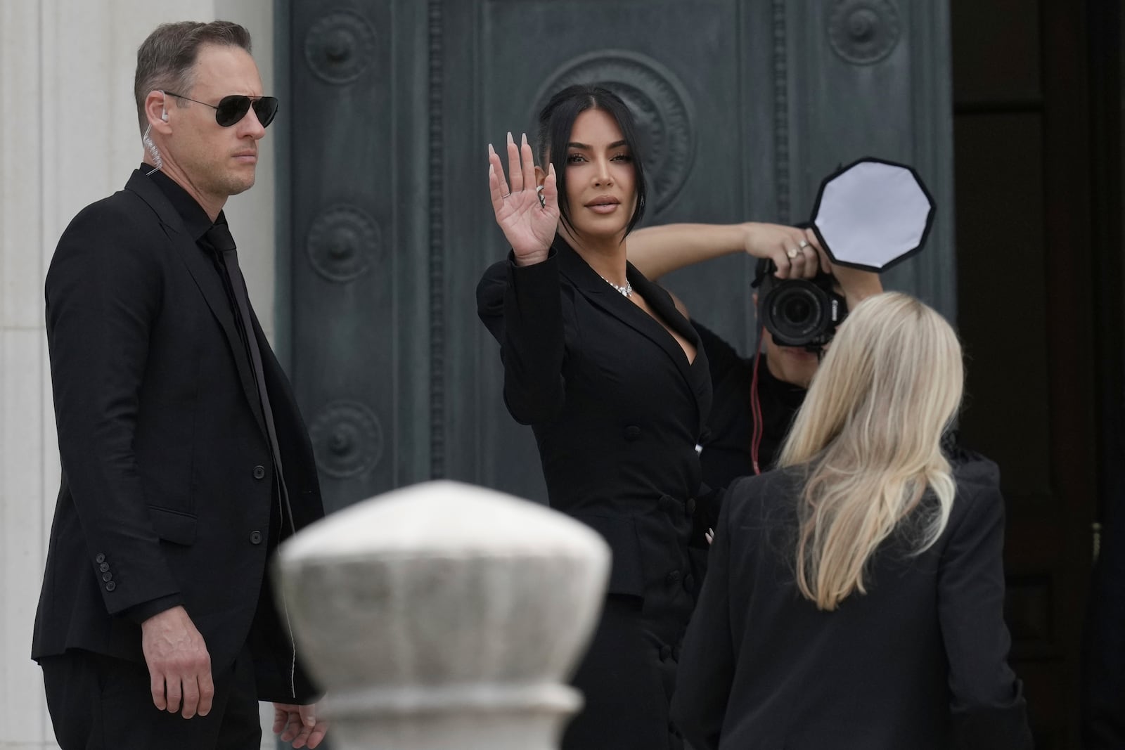 Kim Kardashian waves as she arrives to testify regarding a robbery of millions of dollars in jewels from her Paris hotel room in 2016, in Paris, Tuesday, May 13, 2025. (AP Photo/Aurelien Morissard)