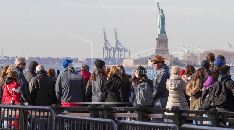 FILE - In this Jan. 20, 2018, file photo, visitors to the Statue of Liberty stand in line to board a ferry that will cruise the bay around the statue and Ellis Island in New York. The U.S. Department of Commerce says government statistics showing a decrease in international arrivals may be wrong. The department is suspending publication of the data until it can be revised. Critics have been complaining of a "Trump slump" in international tourism, and arrivals data compiled by the government had validated those concerns until now. The Commerce Department says some international arrivals may have been miscategorized as U.S. residents, leading to an undercount. (AP Photo/Mary Altaffer, File)