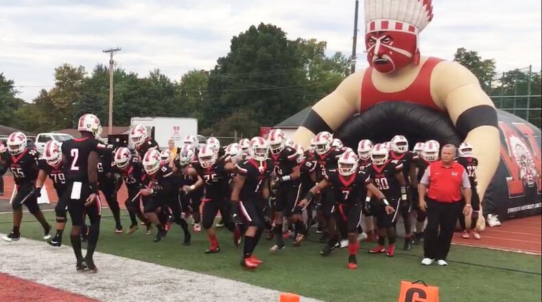 Wayne Warriors football players emerge from an inflatable tunnel topped by a red-faced Indian wearing a headdress before their home game against Northmont on Friday, Sept. 21, 2018. MARC PENDLETON / STAFF