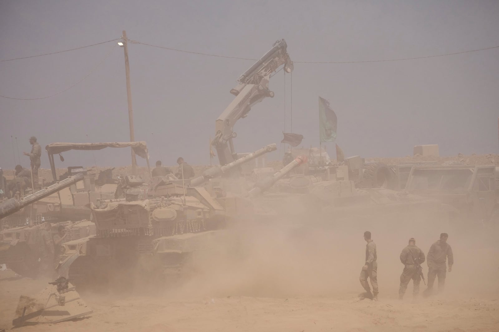 Israeli soldiers work on their tanks in a staging area on the border with Gaza Strip, in southern Israel, Tuesday, July 29, 2025. (AP Photo/Ariel Schalit)