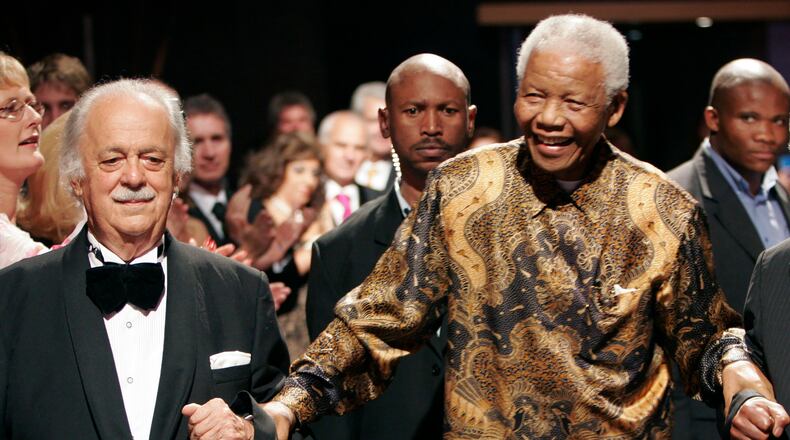 FILE — In this Wednesday Nov. 12, 2008 file photo George Bizos, left, anti-apartheid activist, and life-long friend and lawyer of Nelson Mandela, right, arrives for his 80th birthday party in Johannesburg, South Africa. Bizos has died Wednesday Sept. Sept. 9, 2020, aged 92. (AP Photo/Denis Farrell)