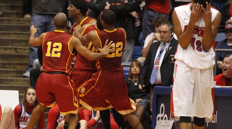 Southern California’s Pe’Shon Howard is mobbed by his teammates after making the game-winning 3-pointer at the buzzer in overtime as Dayton guard Vee Sanford walks away with his head in his hands Sunday, Dec. 22, 2013, at UD Arena.