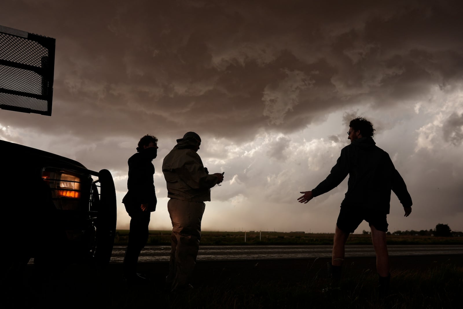 Joey Toniolo, from left, Tim Marshall and Tony Illenden stand next to Northern Illinois University's Husky Hail Hunter as storm clouds gather during a Project ICECHIP operation Friday, June 6, 2025, in Meadow, Texas. (AP Photo/Carolyn Kaster)