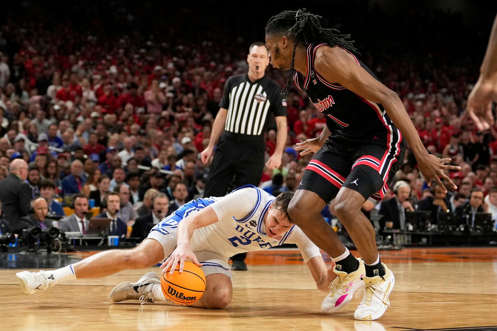 Duke forward Cooper Flagg slips as Houston forward Joseph Tugler looks on during the second half in the national semifinals at the Final Four of the NCAA college basketball tournament, Saturday, April 5, 2025, in San Antonio. (AP Photo/Brynn Anderson)