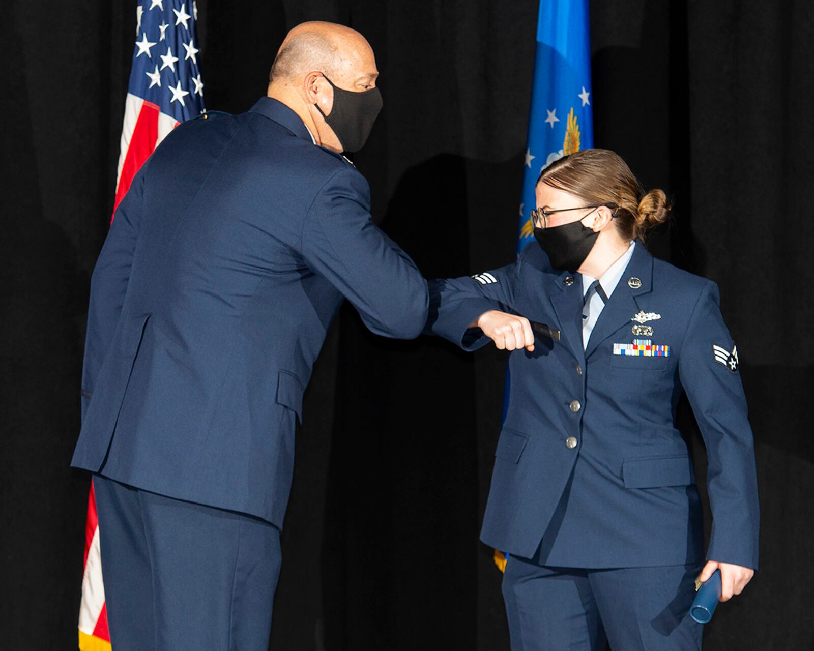 Col. Patrick Miller, 88th Air Base Wing and installation commander, bumps elbows with Senior Airman Tanner Murray, National Air and Space Intelligence Center, as she is awarded her Community College of the Air Force degree Nov. 19 at the National Museum of the Air Force. Murray was one of 29 Wright-Patterson Airmen earning their degrees. U.S. AIR FORCE PHOTO/R.J. ORIEZ