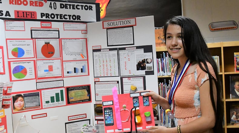 Jianna Nichols, 13, of Tipp City discusses her project board which received national recognition during an invention convention competition in Michigan in June. Contributed.