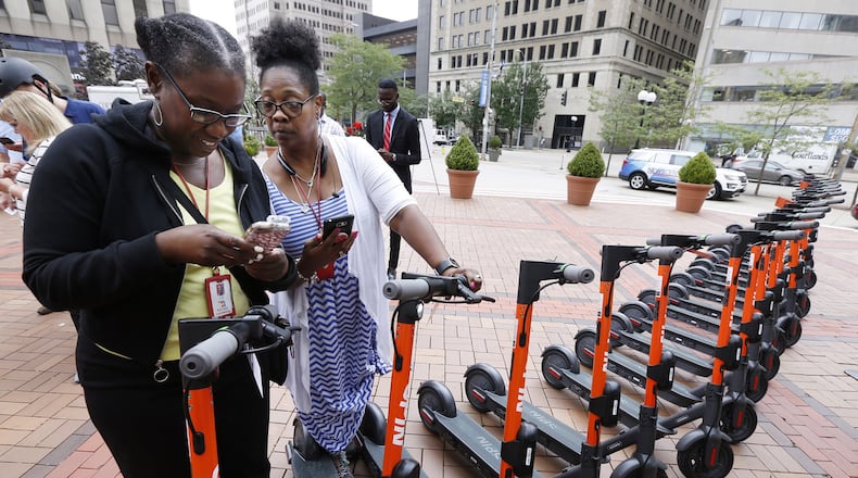 Lettia Younger, left, and Sheila Back log into the Spin Electric Scooters app at Courthouse Square before taking a test ride on the electric scooters. TY GREENLEES / STAFF