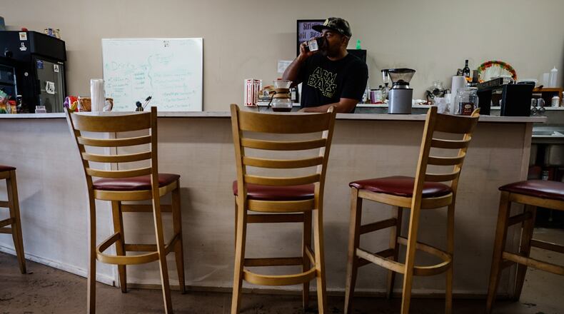 Rob Dejene owner of Nimbus Comic Cafe serves up coffee at his shop on East Main Street in Trotwood. JIM NOELKER/STAFF