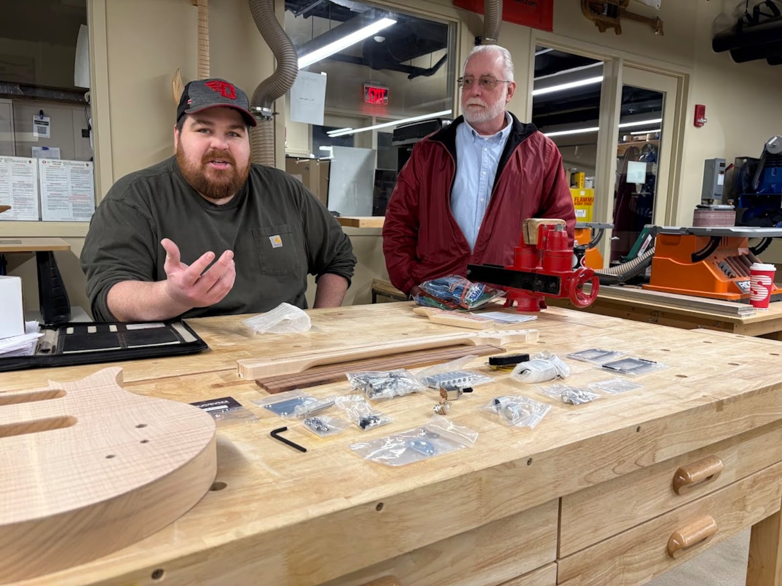 Matt Mongin, seated, a Sinclair Community College adjunct faculty member, and Andrew Shaffer, manager of Sinclair's Guitar Lab, with elements of the guitar-building educational kits Shaffer's team assembles arrayed on a table in a class in Sinclair's building 8. The kits allow educators to guide students in the process of building their own guitars. Shaffer estimates that he and his team have sold perhaps 25,000 of the kits since about 2008. THOMAS GNAU/STAFF