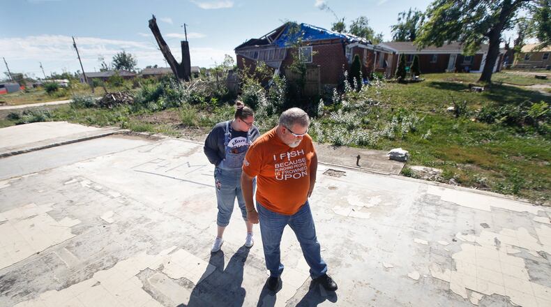 Ed Kirklin and his daughter Kenzie Banta walk over the slab foundation where their house once sat on Crosswell Avenue in Brookville. Kirklin decided to move the family to Englewood and plans not to rebuild. CHRIS STEWART / STAFF