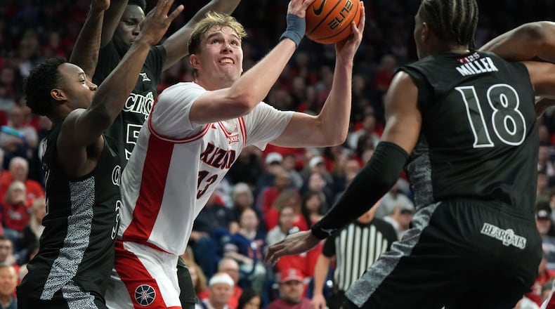 Arizona center Motiejus Krivas scores in between Cincinnati guard Grant Darbyshire (13), guard Sencire Harris (5), and forward Baba Miller during the second half of an NCAA college basketball game, Wednesday, Jan. 21, 2026, in Tucson, Ariz. (AP Photo/Rick Scuteri)