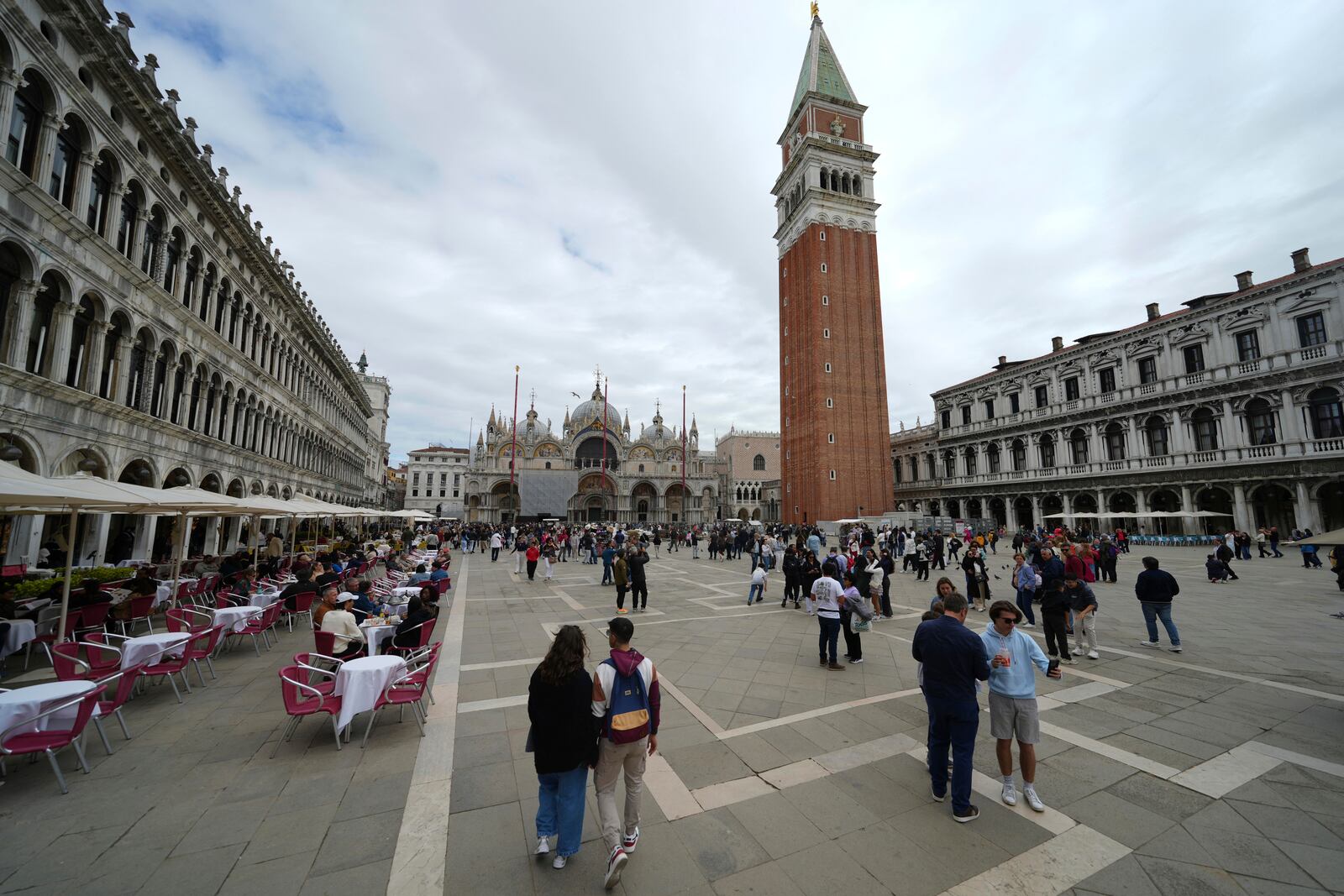 People walk in San Marco square in Venice, Italy, Friday, April 18, 2025, Venice on Friday launches for a second year a pilot program to charge day-trippers an entrance fee. (AP Photo/Antonio Calanni)