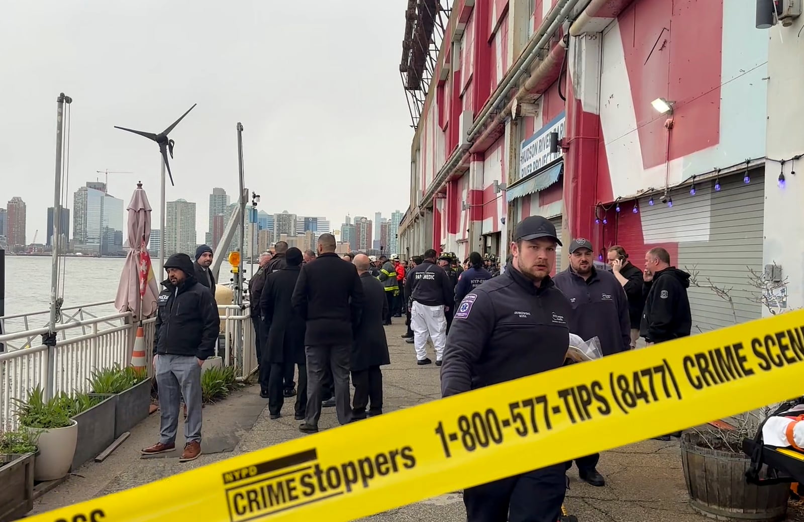 First responders walk along Pier 40, Thursday, April 10, 2025, in New York, across from where a helicopter went down in the Hudson River in Jersey City, N.J. (AP Photo/Jennifer Peltz)