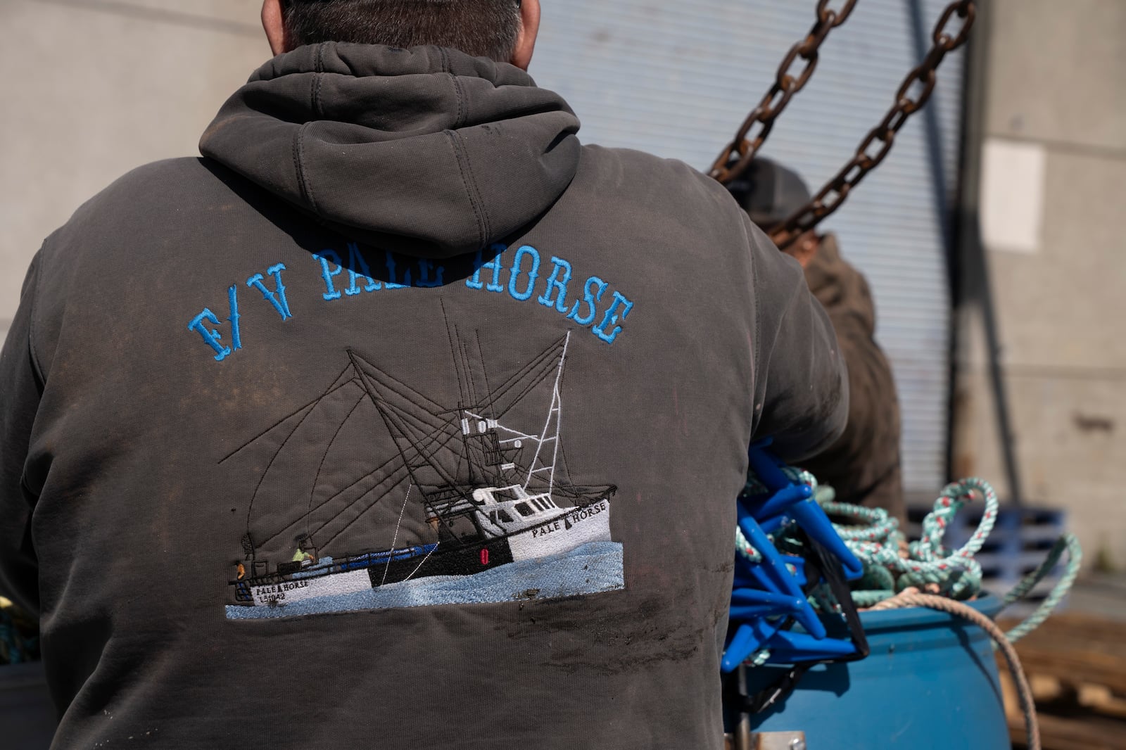 San Francisco Dungeness crab fisherman Brand Little wears a sweatshirt featuring his boat, Pale Horse, as he loads rope onto his boat at Pier 45 in San Francisco, Thursday, April 10, 2025. Little is part of a pilot program using pop-up gear to protect whales. (AP Photo/Emily Steinberger)