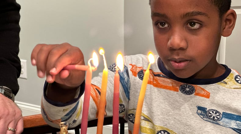 Adam Kulbersh's son, Jack, lights the Hanukkah menorah. CONTRIBUTED
